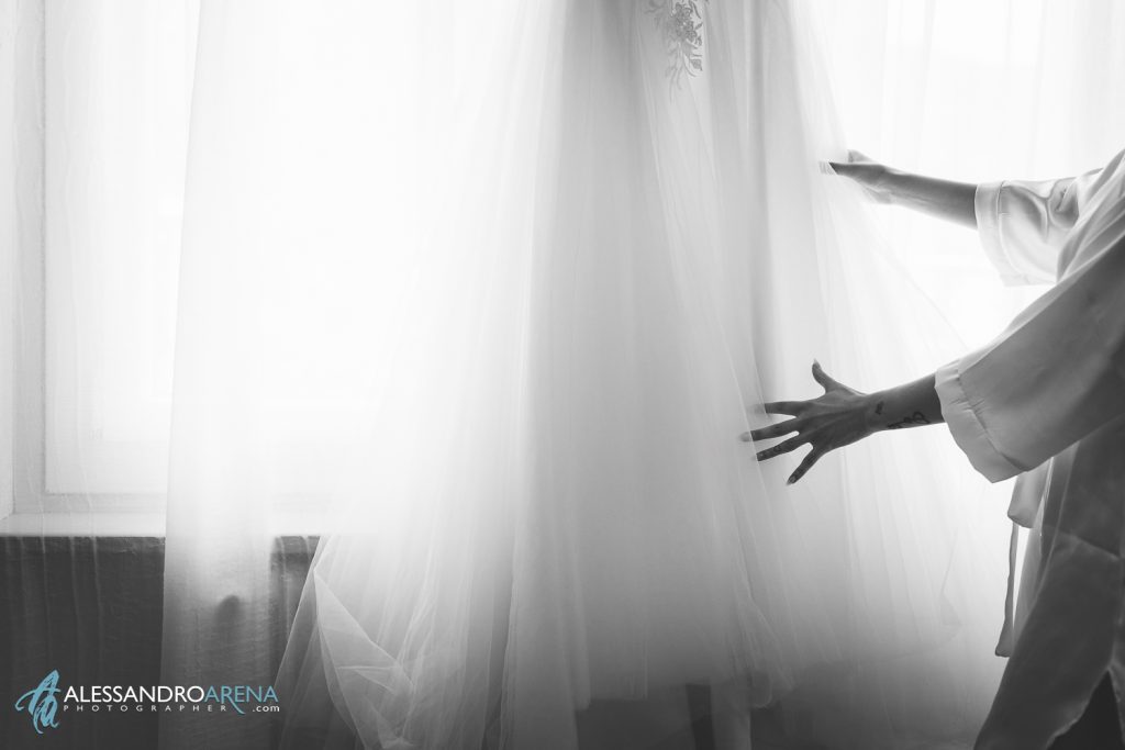 Dettaglio della mano della sposa che sistema l'abito prima di indossarlo