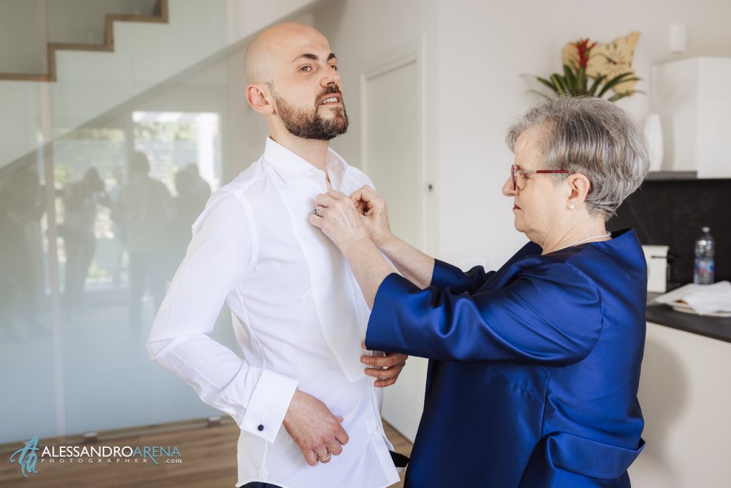 La mamma aiuto lo sposo con la vestizione