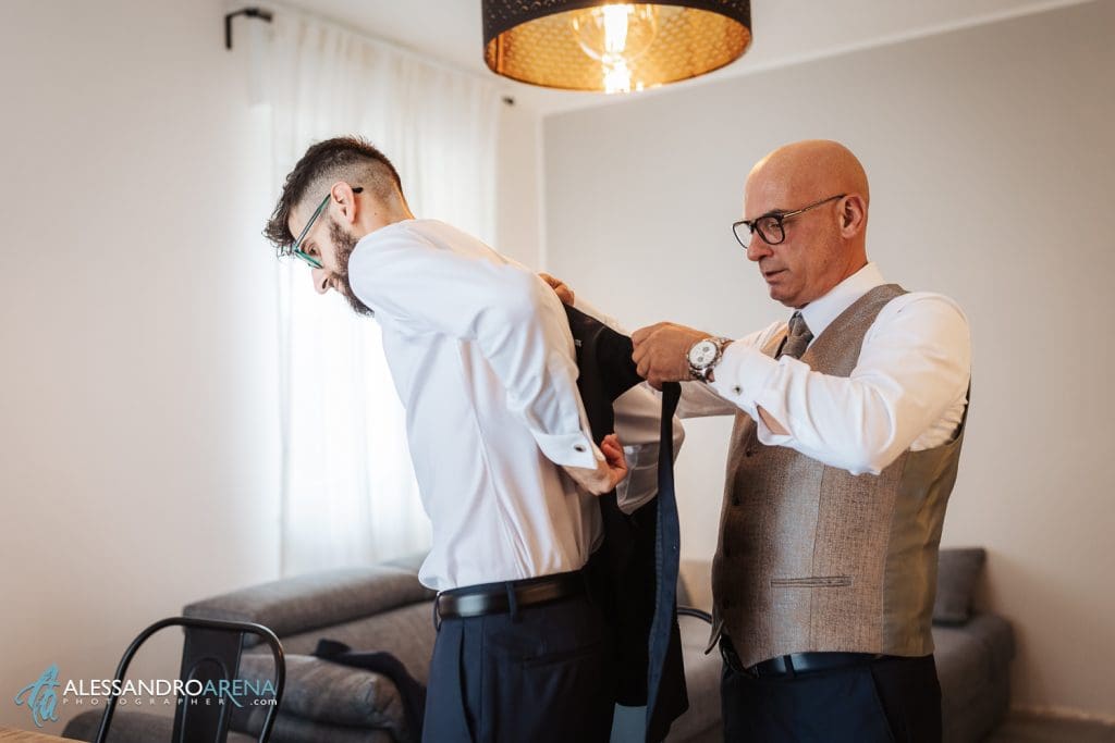 Il papà dello sposo lo aiuta a indossare il gilet